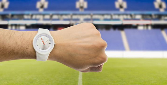 Man with wrist turned to show watch time in front of empty stadium stand